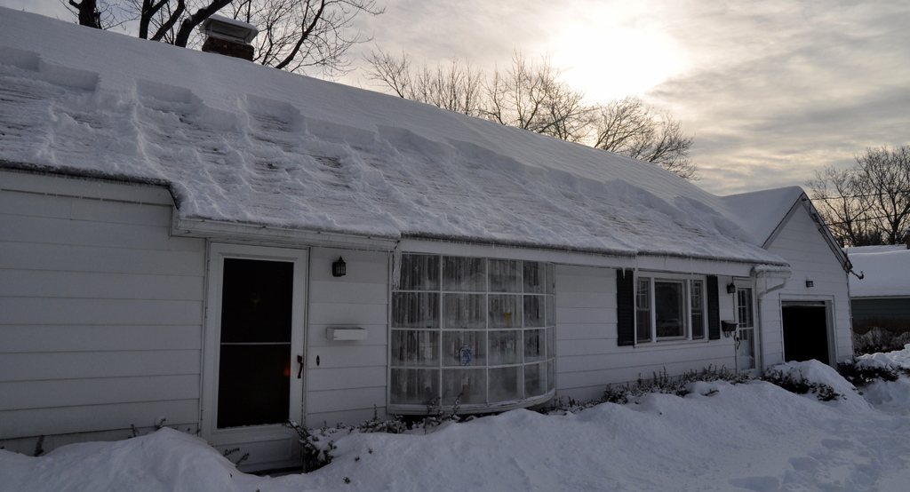 White house with a snow-covered roof on a bright winter day