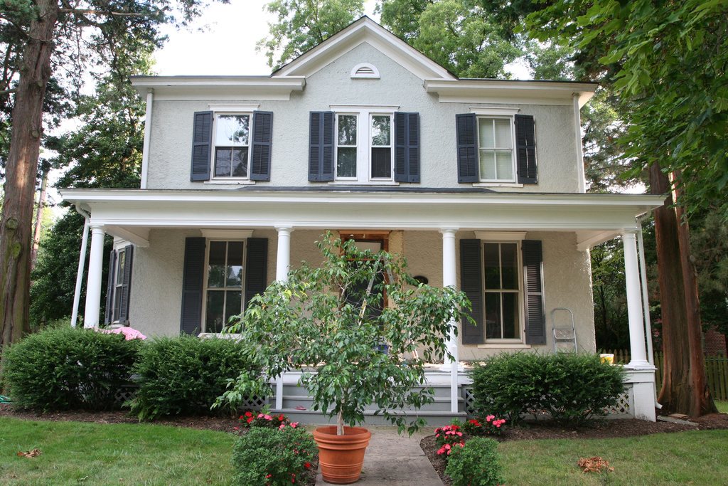 White two-storey house with black shutters and a welcoming front porch